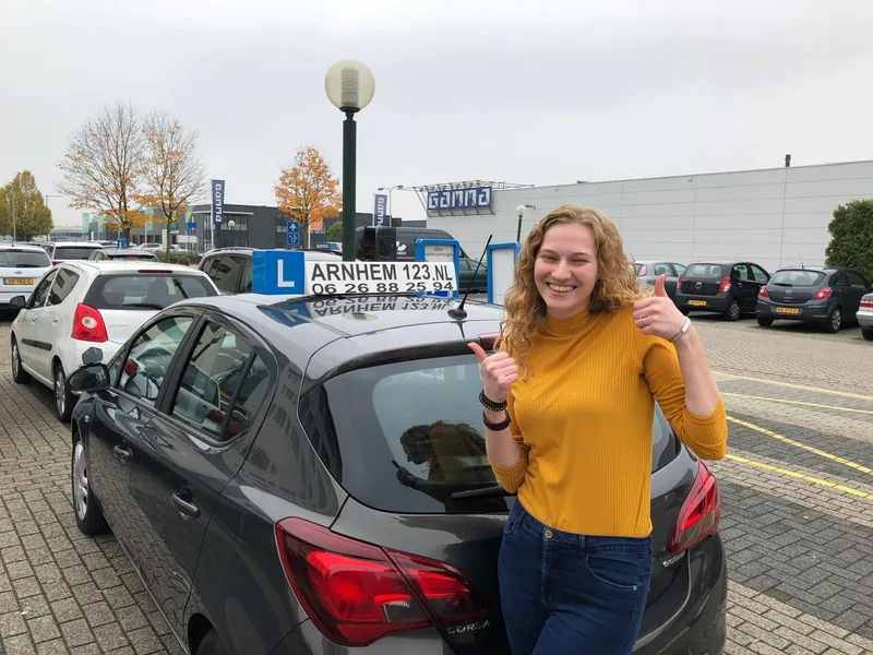 Geslaagde leerling naast een lesauto van Rijschool Arnhem 123