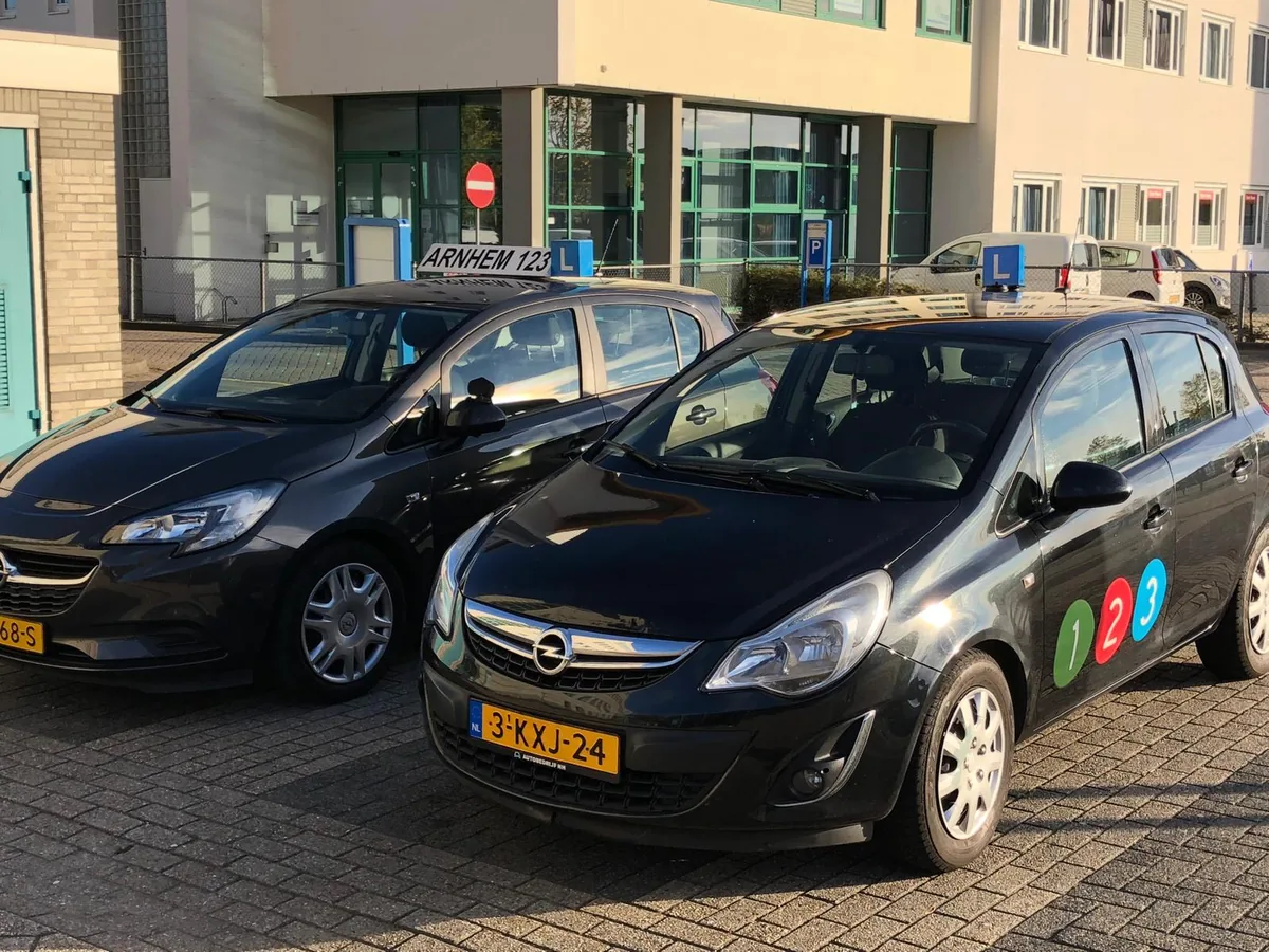 Twee Opel-lesauto’s van Rijschool Arnhem 123 met lesborden